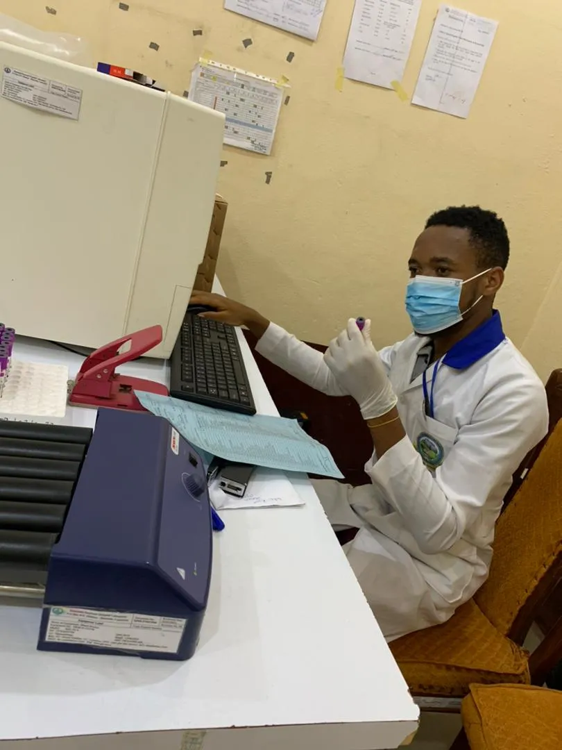 Nsom Emmanuel in a lab coat and mask working at a laboratory bench