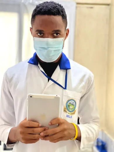Nsom Emmanuel in a lab coat holding a tablet