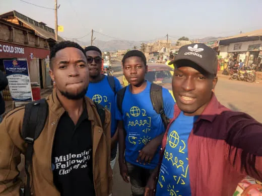 Nsom Emmanuel taking a street selfie with a team in matching blue t-shirts