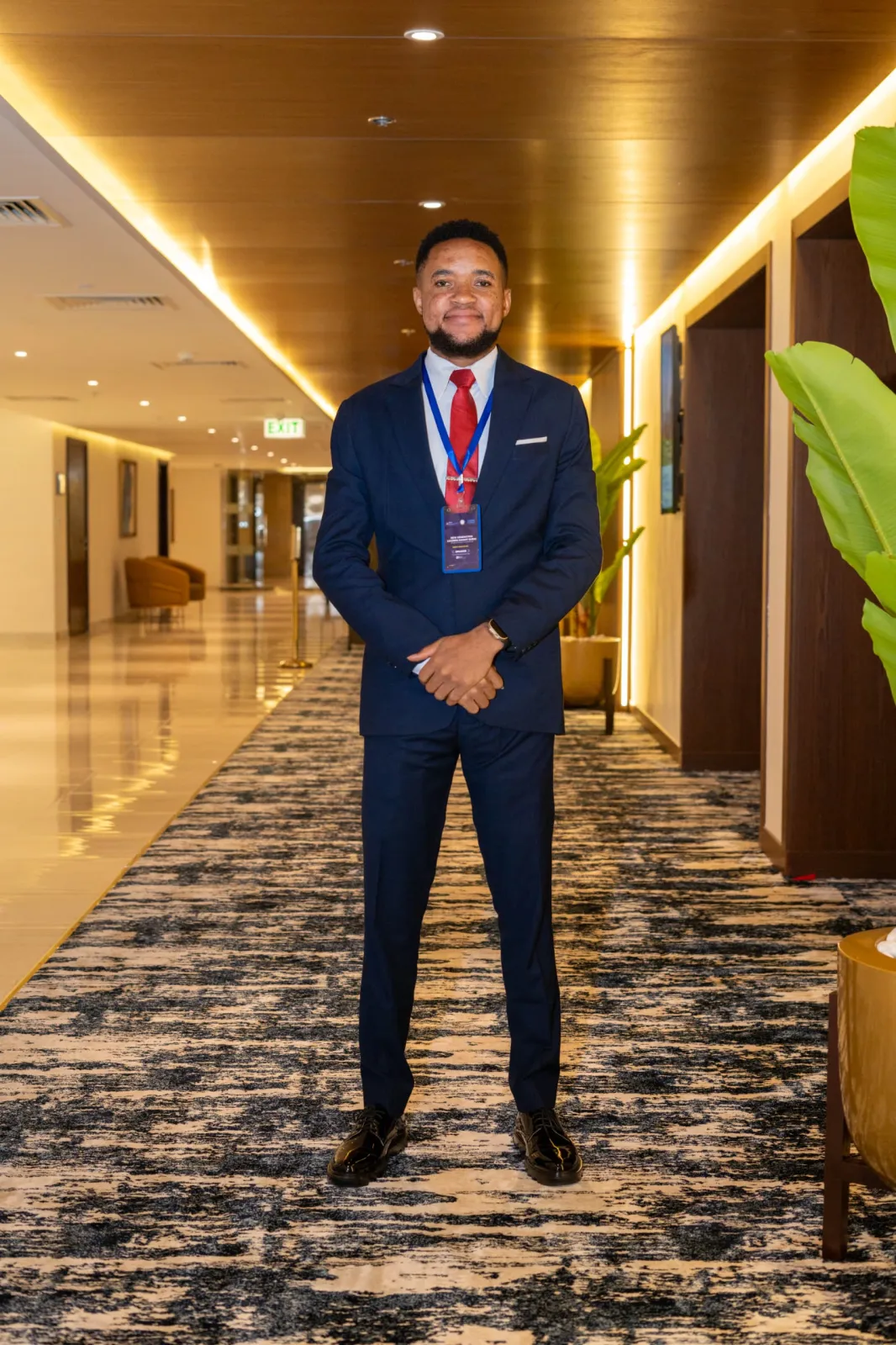 Nsom Emmanuel in a navy suit wearing a conference lanyard